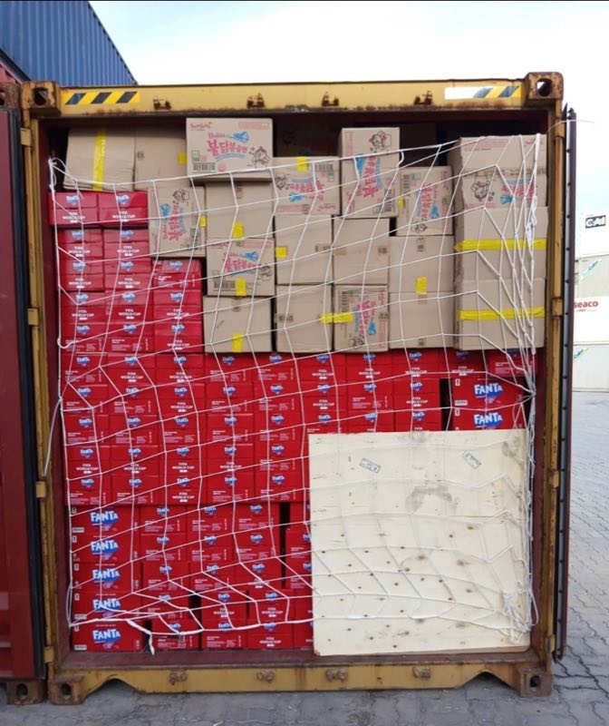 Shipping container loaded with cartons of Samyang Buldak ramen, secured with cargo netting for export